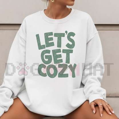 Front view of the festive friction sweatshirt displaying 'Let's Get Cozy' seasonal graphic typography across the chest of a soft green fleece crewneck pullover. - dogmomhat